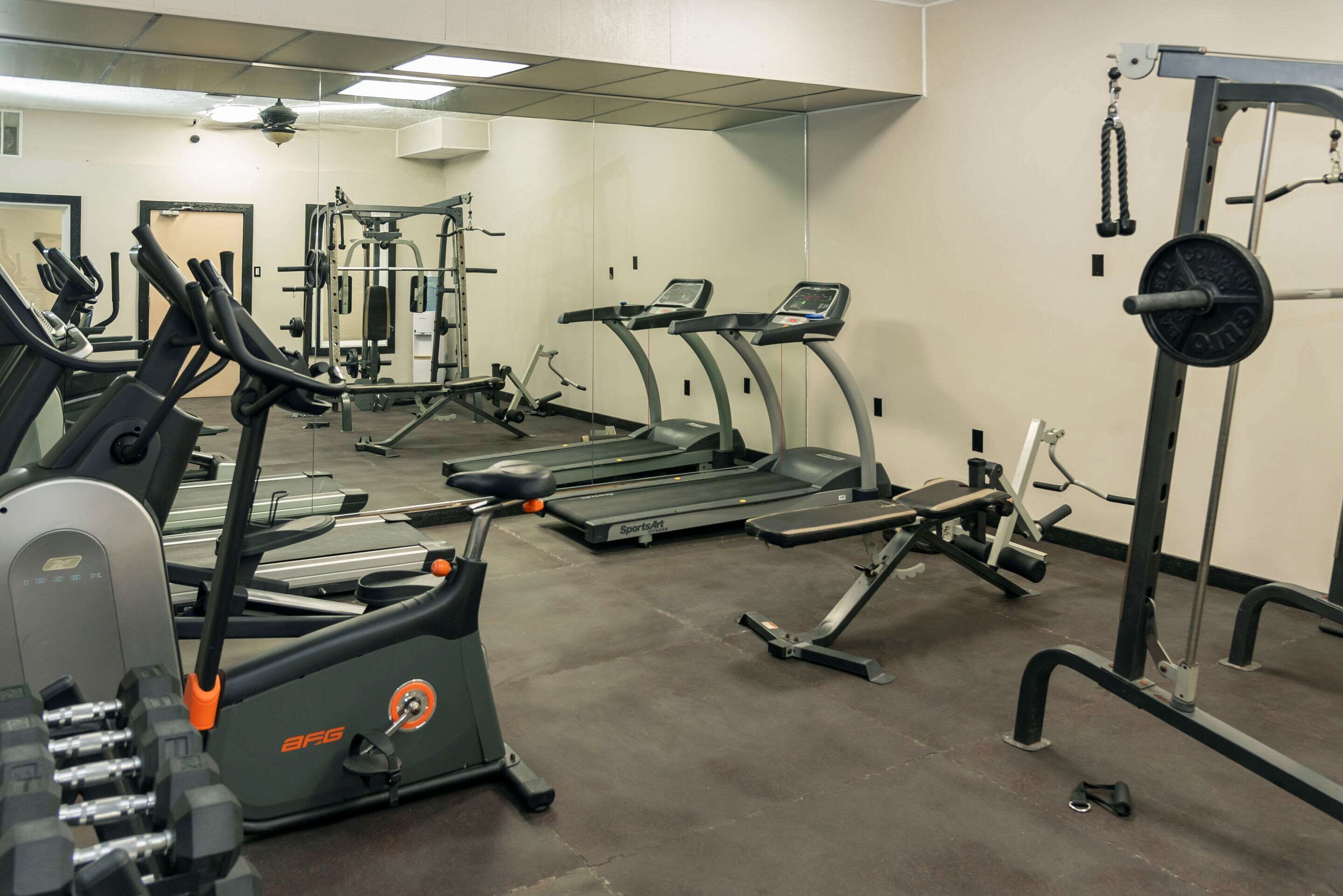 Ein Fitnessstudio mit Laufbändern, Crosstrainern und Gewichten.