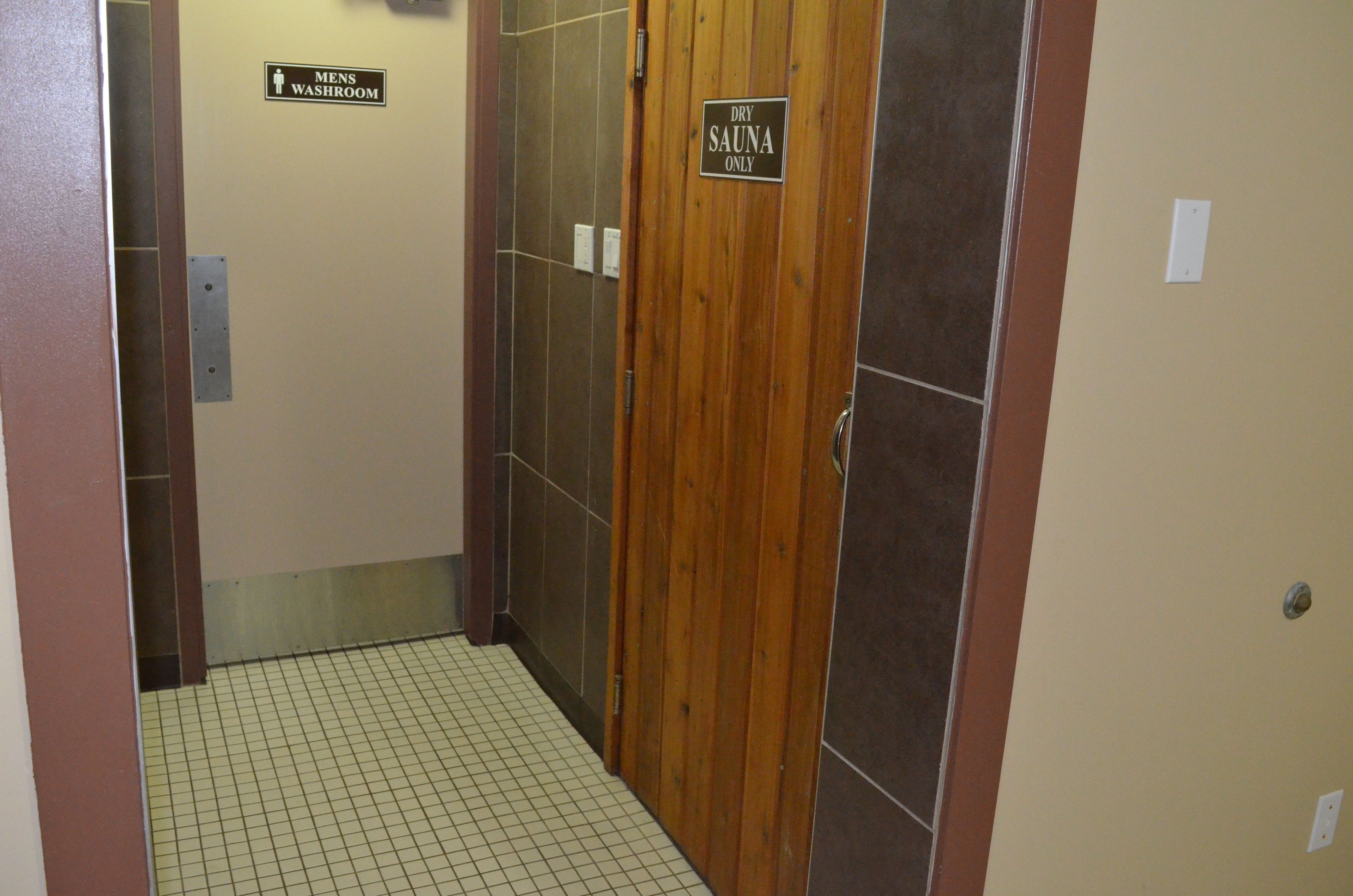 Un pasillo con un cartel que indica el baño para hombres y otro para la sauna seca.