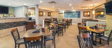 A restaurant with multiple tables and booths, a bar area, and a television screen.