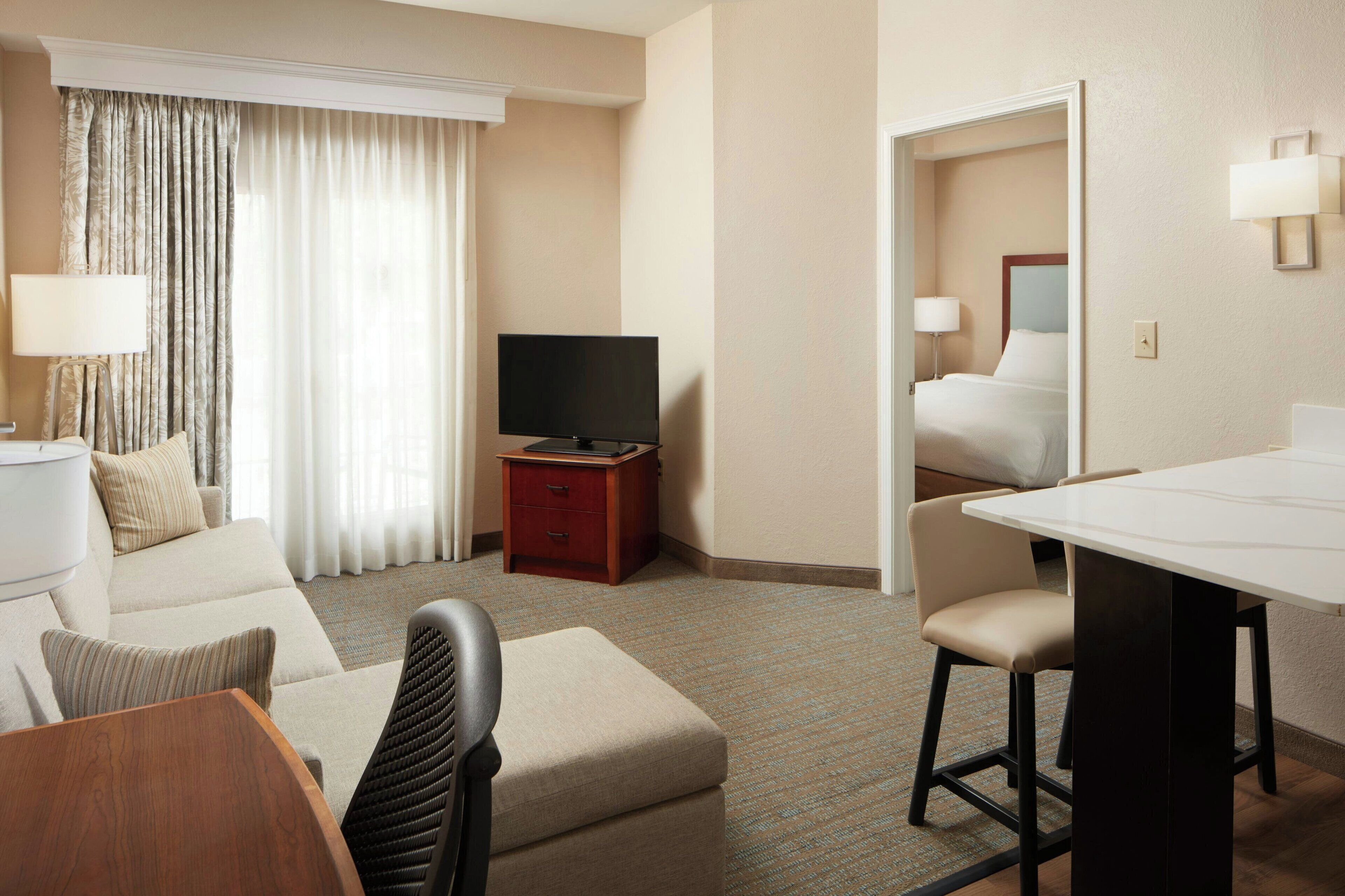 Una habitación de hotel con sofá, televisión, una mesita y cama.