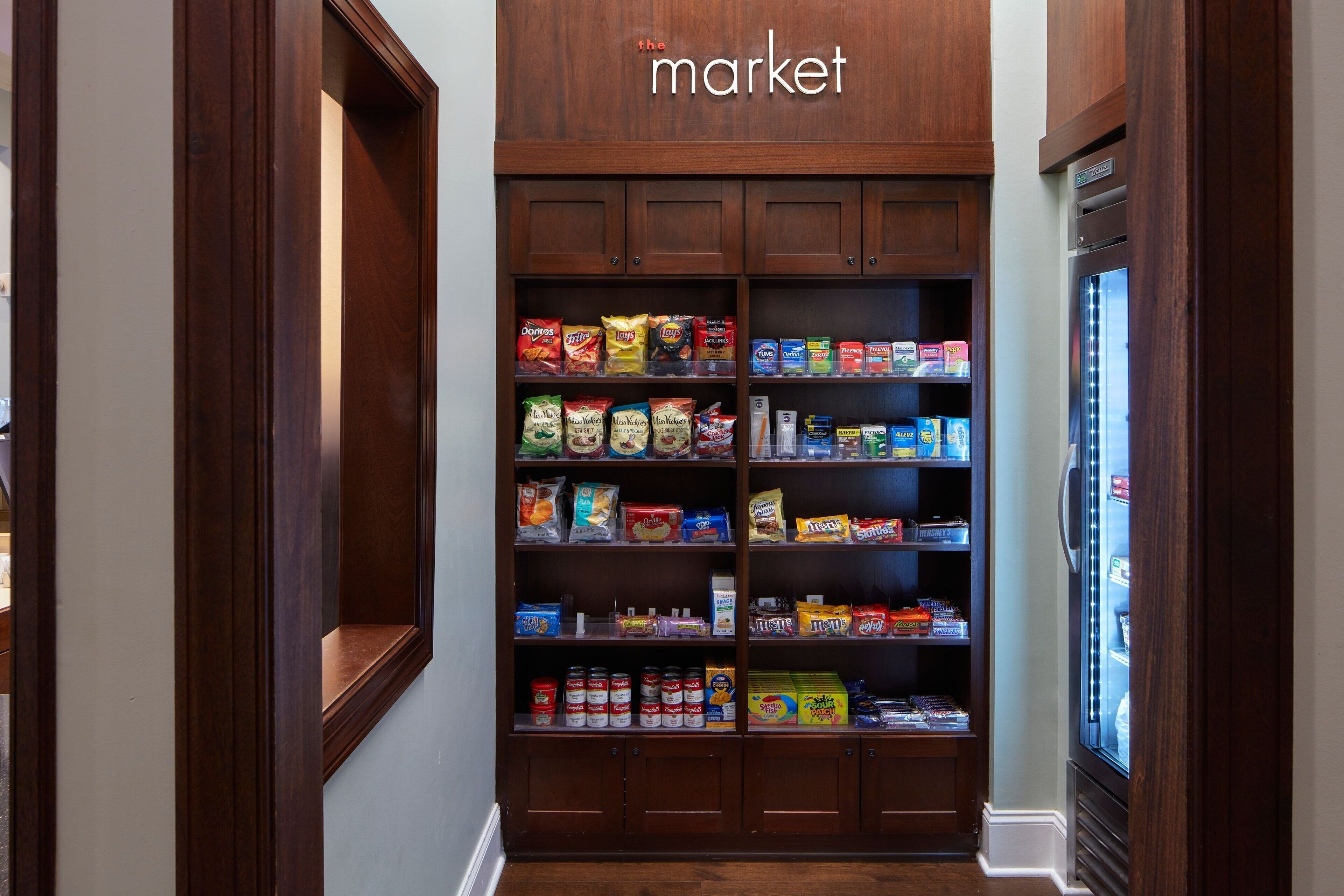 A wooden pantry with shelves stocked with snacks, canned goods, and boxed items.