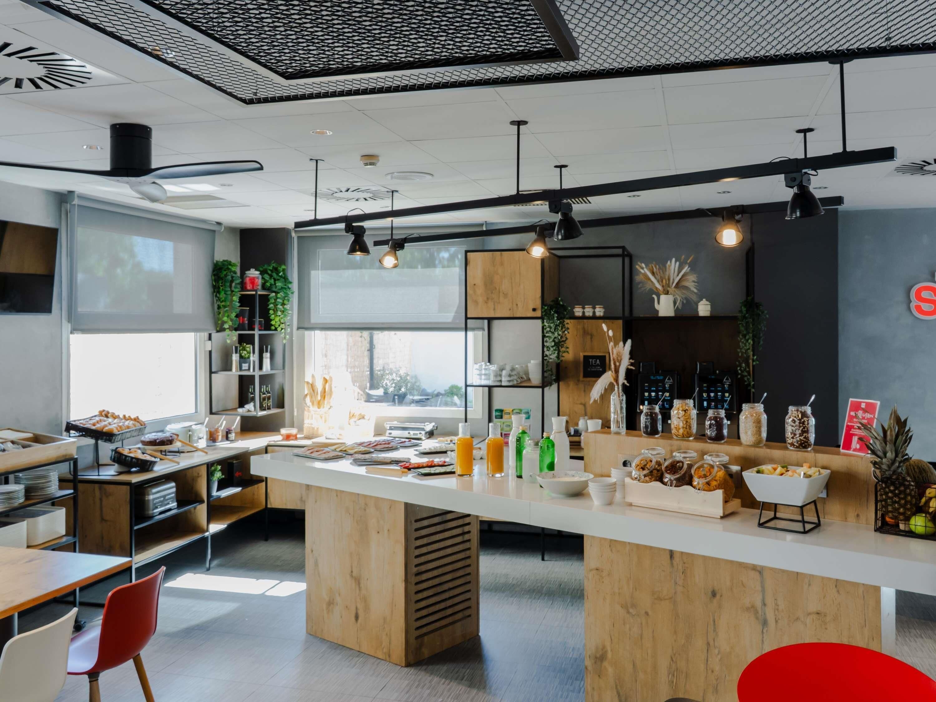 A modern café with a central island, seating area, and a view of the city.
