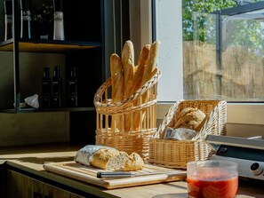 A kitchen counter with a basket of baguettes, a loaf of bread, and a glass of red drink. - ibis Barcelona Castelldefels (Castelldefels)
