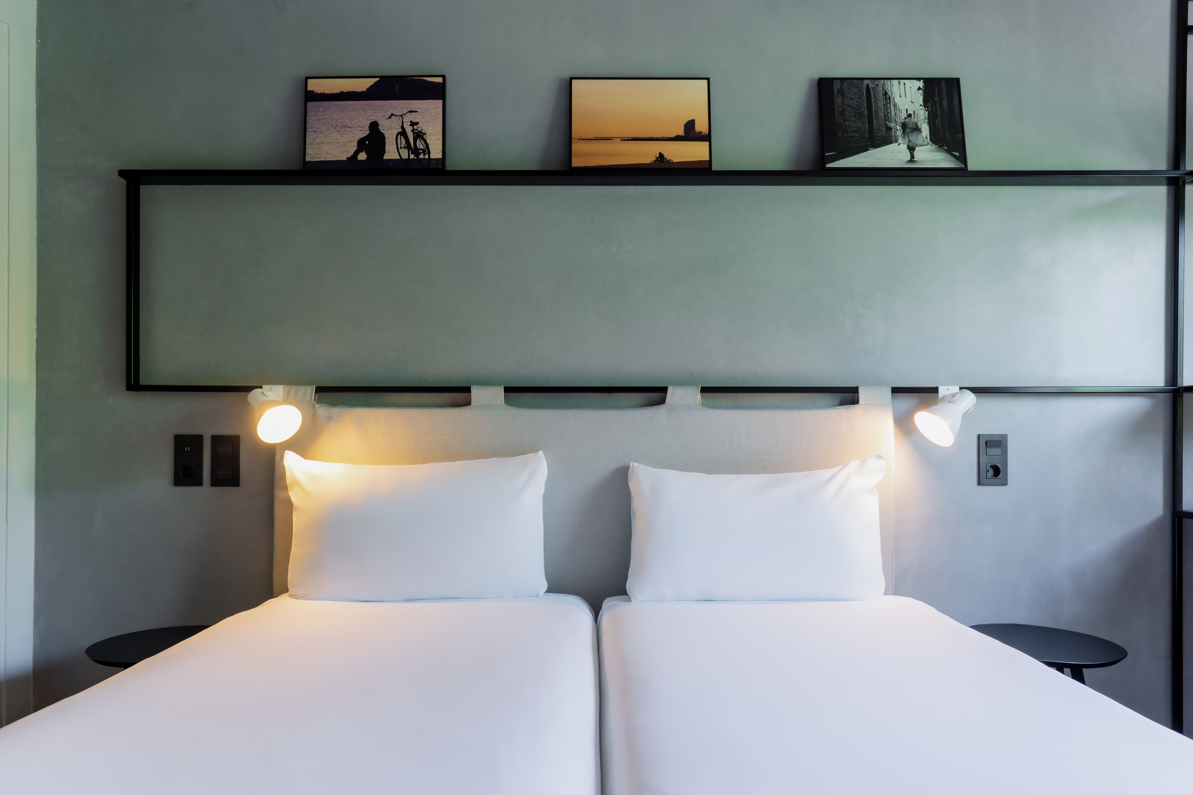 Ein Doppelbett mit weißer Bettwäsche, zwei Nachttische, ein Wandregal mit Kunstwerk und ein Kopfteil mit integrierter Beleuchtung.