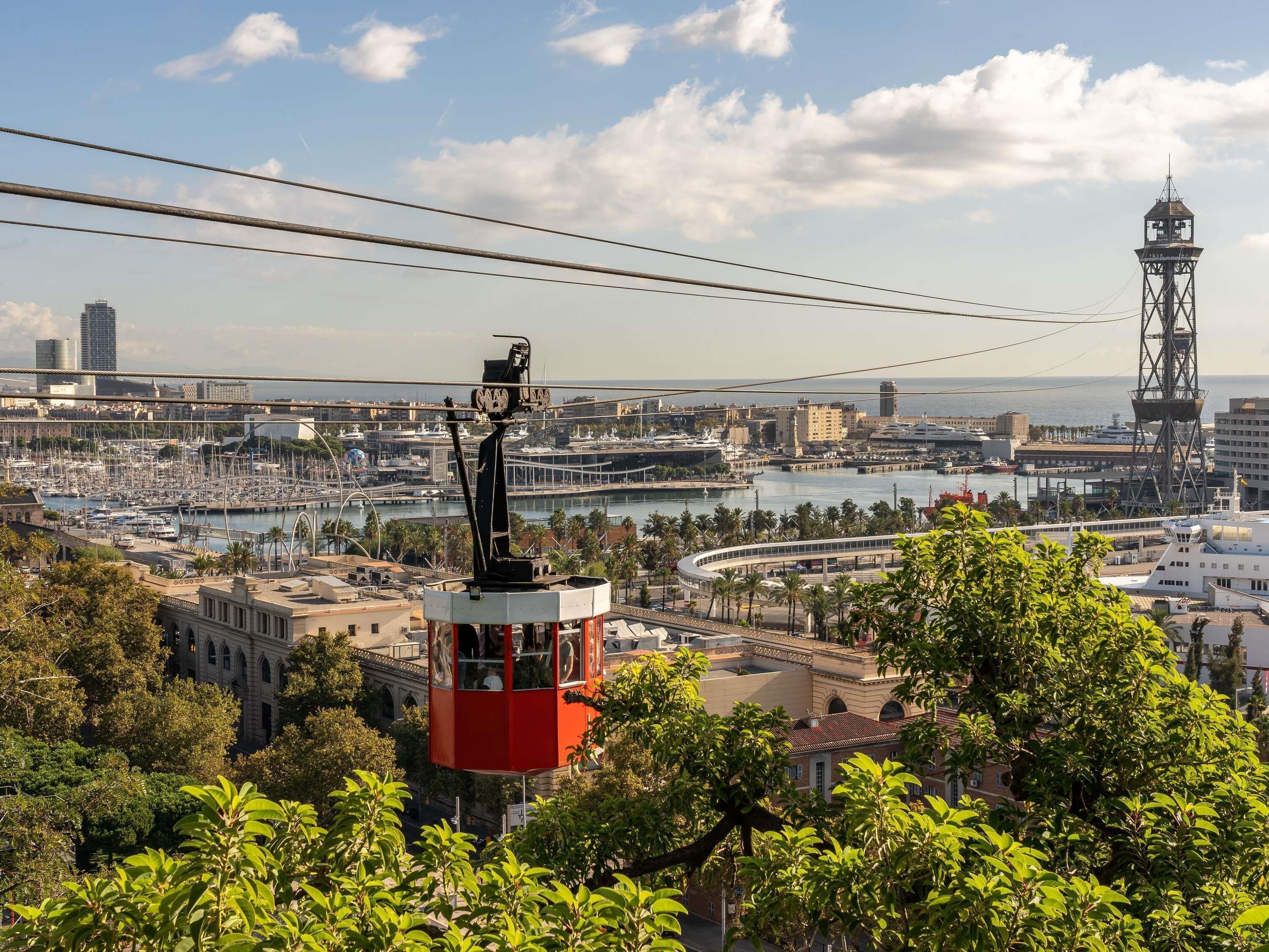 Un sistema de teleférico con vista a un puerto deportivo, edificios y una torre.