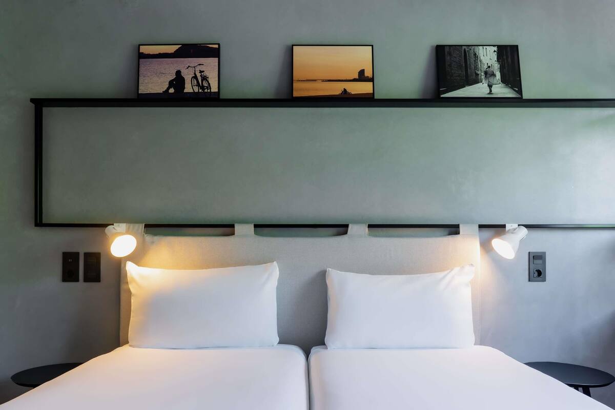 A double bed with two bedside tables, a headboard with wall-mounted lights, and three framed pictures above the bed.