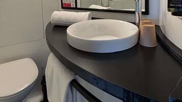 Een badkamer met een witte wastafel, toilet, handdoek en spiegel.
