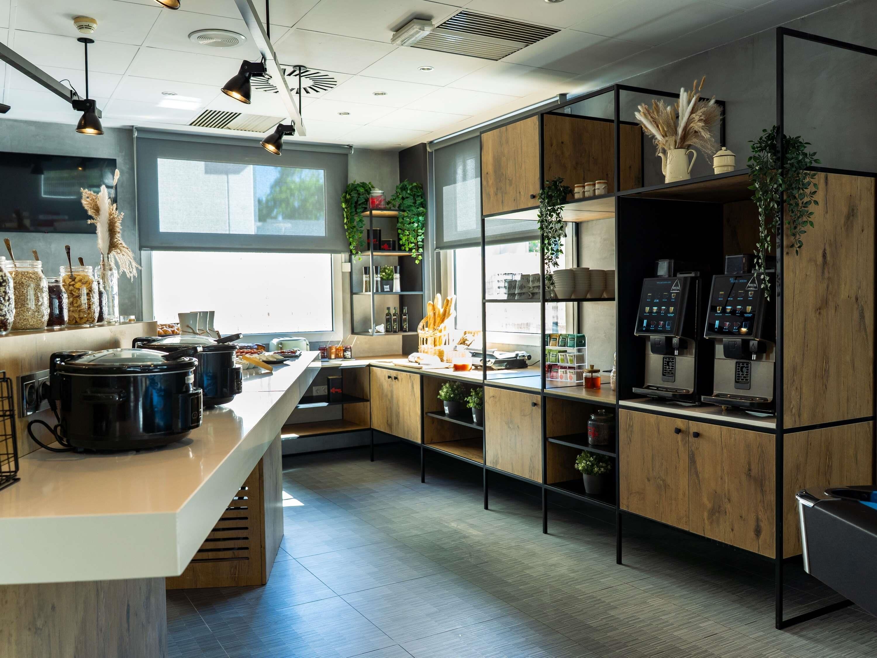 Une cuisine moderne dotée d’un îlot central, d’appareils électroménagers intégrés et offrant une vue sur l’extérieur.