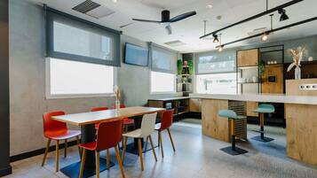 A modern kitchen with wooden cabinets, a bar area, and a dining space with red chairs.