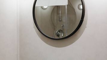 A bathroom with a green sink, a round mirror, and a towel hanging on the wall.