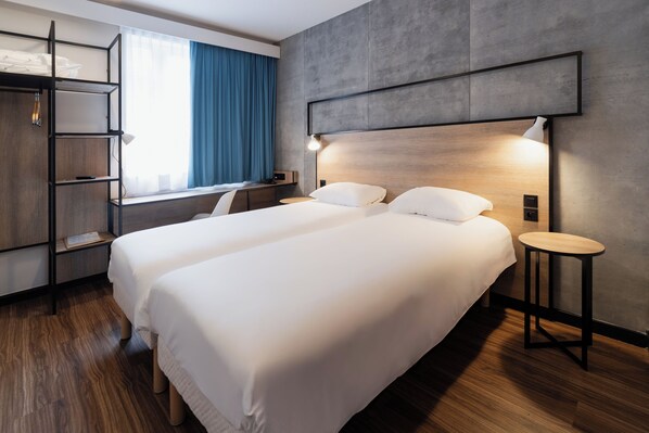 Una habitación de hotel moderna con una cama grande, un escritorio y una estantería.