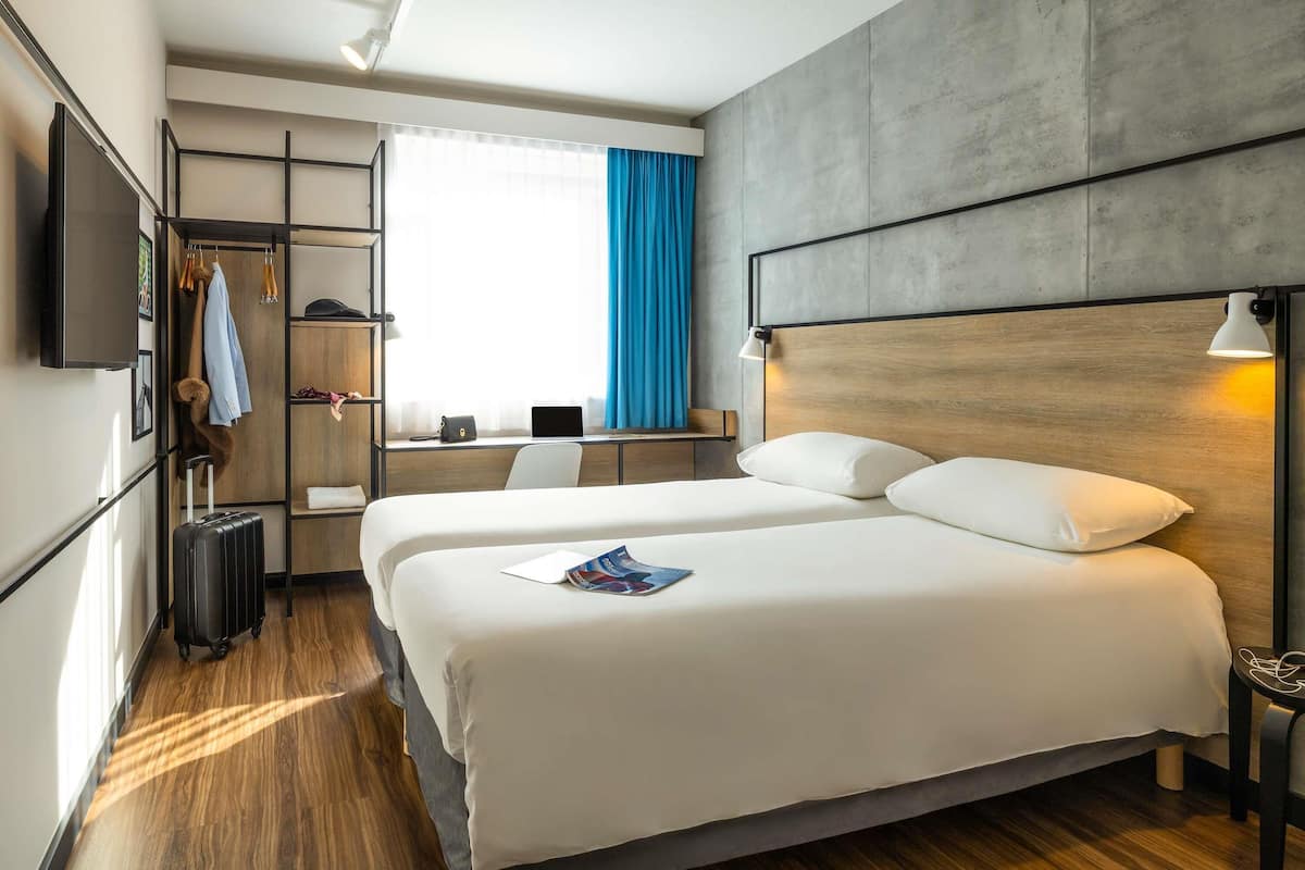 A hotel room with a large bed, a desk, a TV, and a wardrobe.