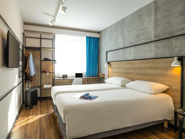 Una habitación de hotel con una cama grande, un escritorio, un televisor y un armario.