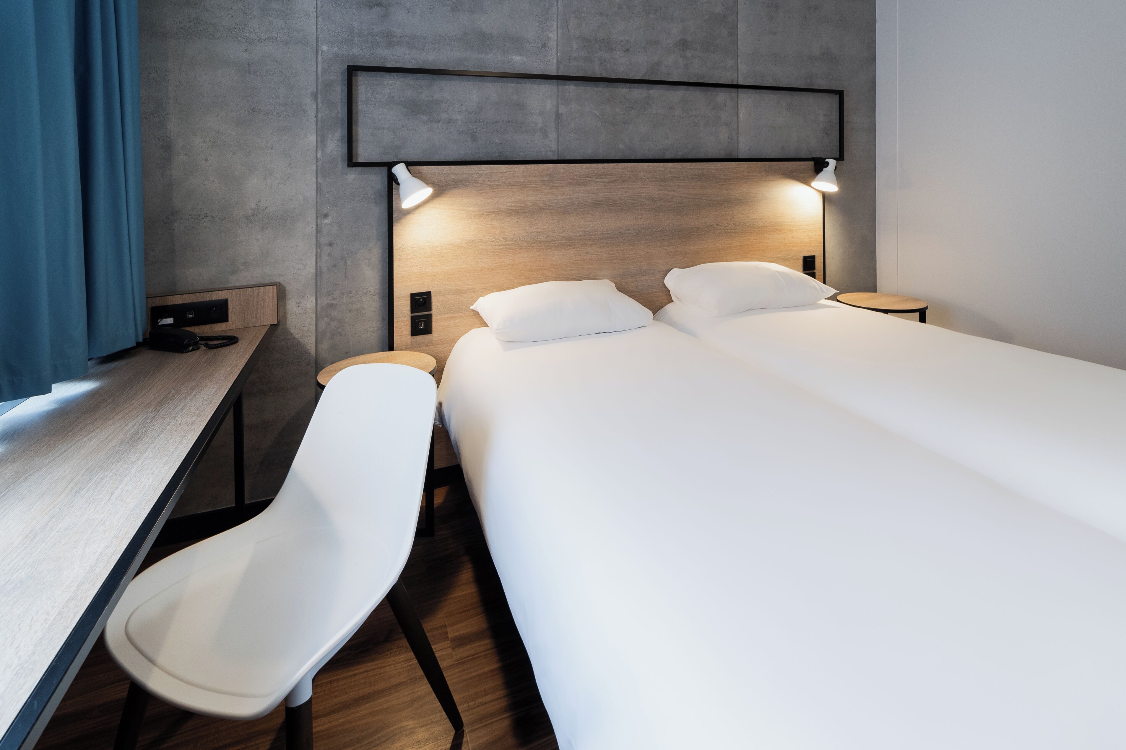 Une chambre d’hôtel moderne, dotée d’un grand lit, d’un bureau et d’une chaise.