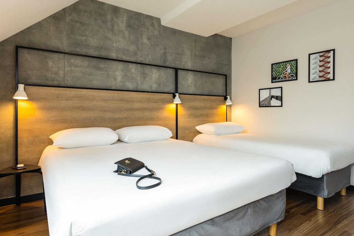 A hotel room with two beds, a wooden headboard, and bedside lamps.
