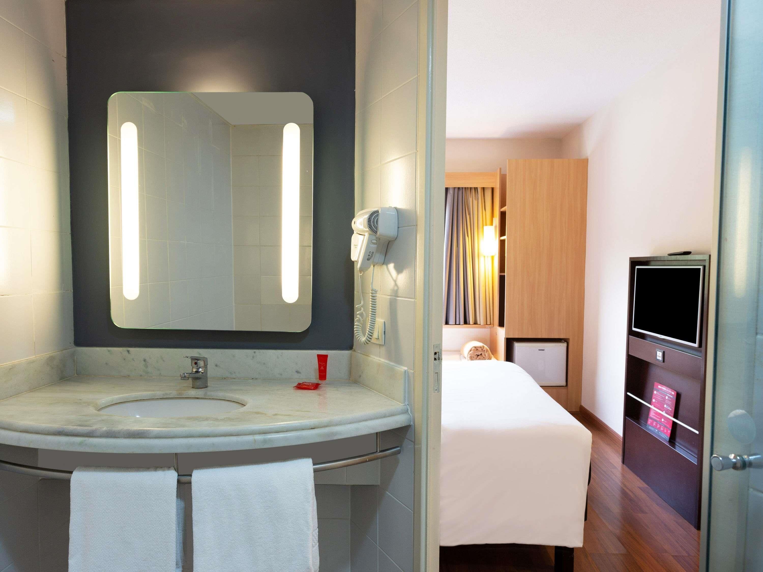 A bathroom with a sink, mirror, towel rack, and a hairdryer.