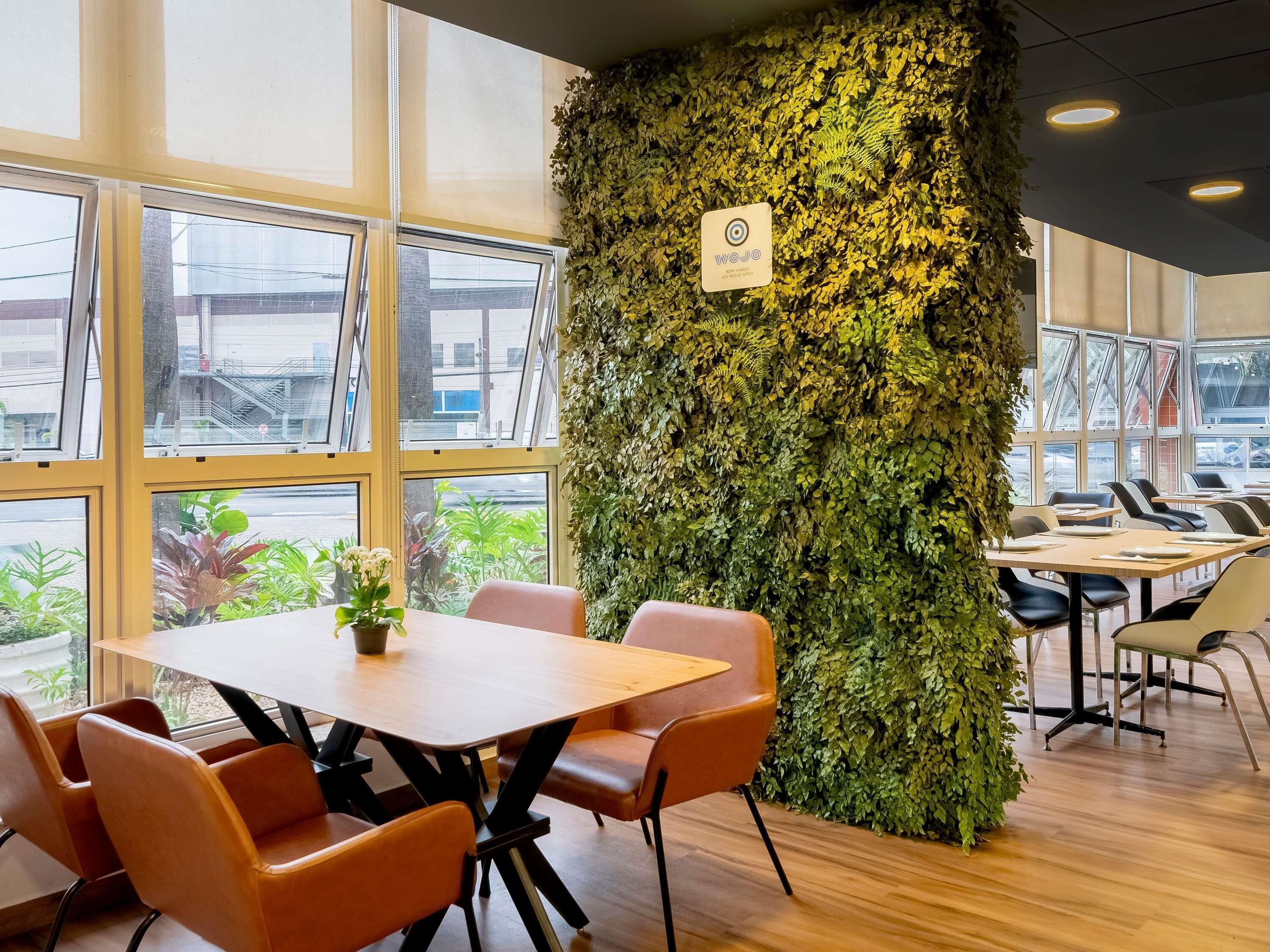 A conference room with a large table, chairs, and a wall covered in greenery.