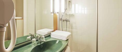 Un baño con un lavamanos verde, un espejo, una ducha y un perchero para toallas.