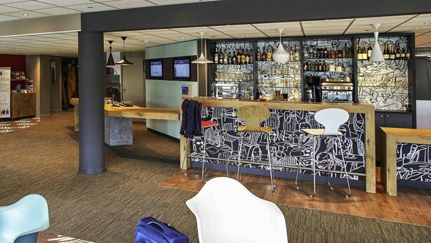 A hotel lobby with a bar area, seating, and a luggage trolley. - ibis Auray (Auray)