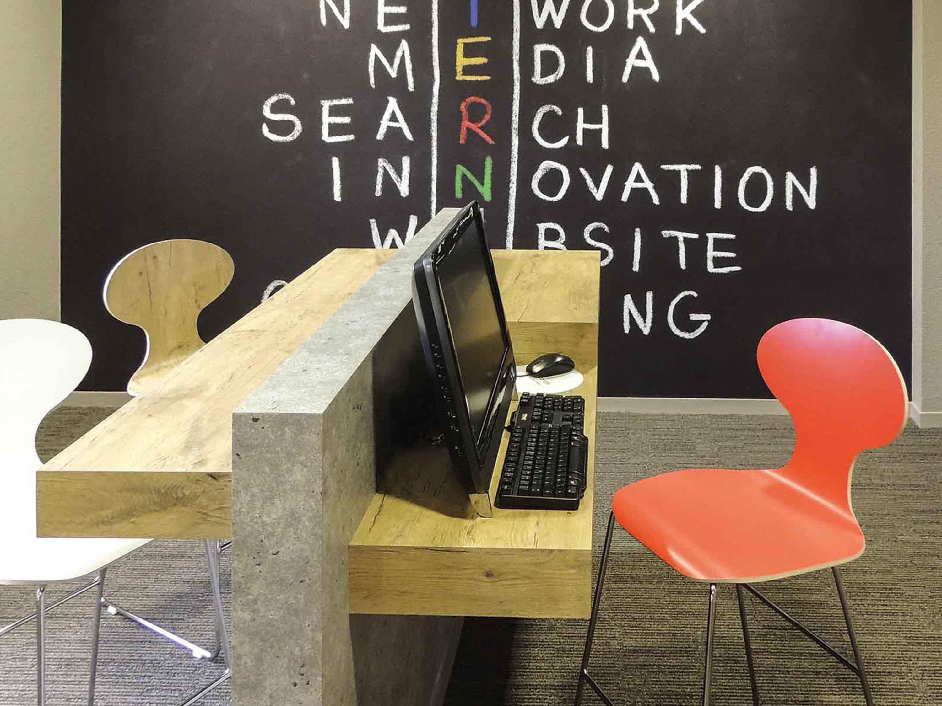Un espacio de trabajo con una computadora portátil, un ratón y una silla roja.