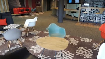 Un área de descanso moderna con diferentes opciones de asientos, incluyendo sofás, sillones y una pequeña mesa.