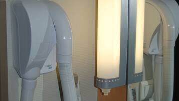 A hair dryer mounted on a wall with a mirror reflecting part of the room.