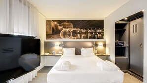 Une chambre d’hôtel comprenant un lit, des tables de chevet, une télévision, un tableau et une armoire.