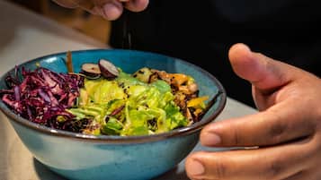 Une personne tenant un saladier rempli d’une salade composée de différents légumes et d’une vinaigrette.