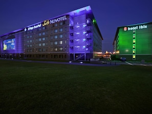 Um hotel com vários andares, com uma placa grande indicando 'Etap Hotel Suite Novotel' e outra placa indicando 'hotel ibis'.