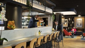Un espace bar moderne comprenant un comptoir, des tabourets de bar et un coin salon avec des chaises.