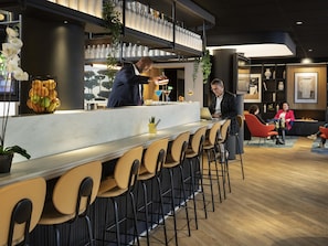 A modern bar area with a counter, bar stools, and a seating area with chairs.