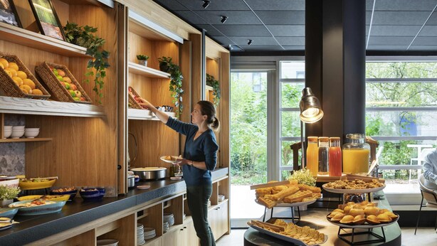 Un buffet de petit-déjeuner proposant une variété d’aliments, avec une personne chargée de servir les clients.