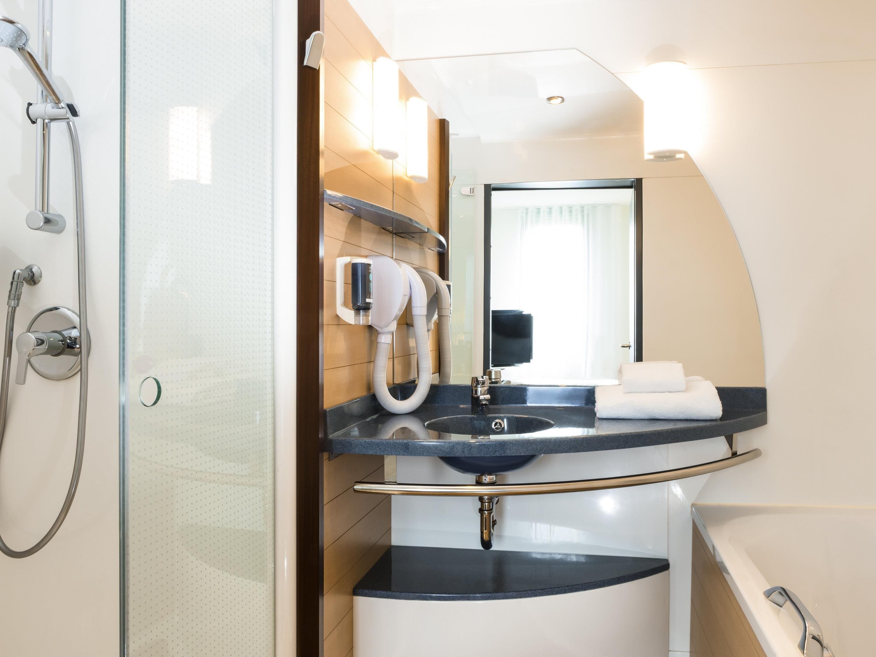 Een moderne badkamer met een douchecabine van glas, een ingebouwd wastafelmeubel en een grote spiegel.