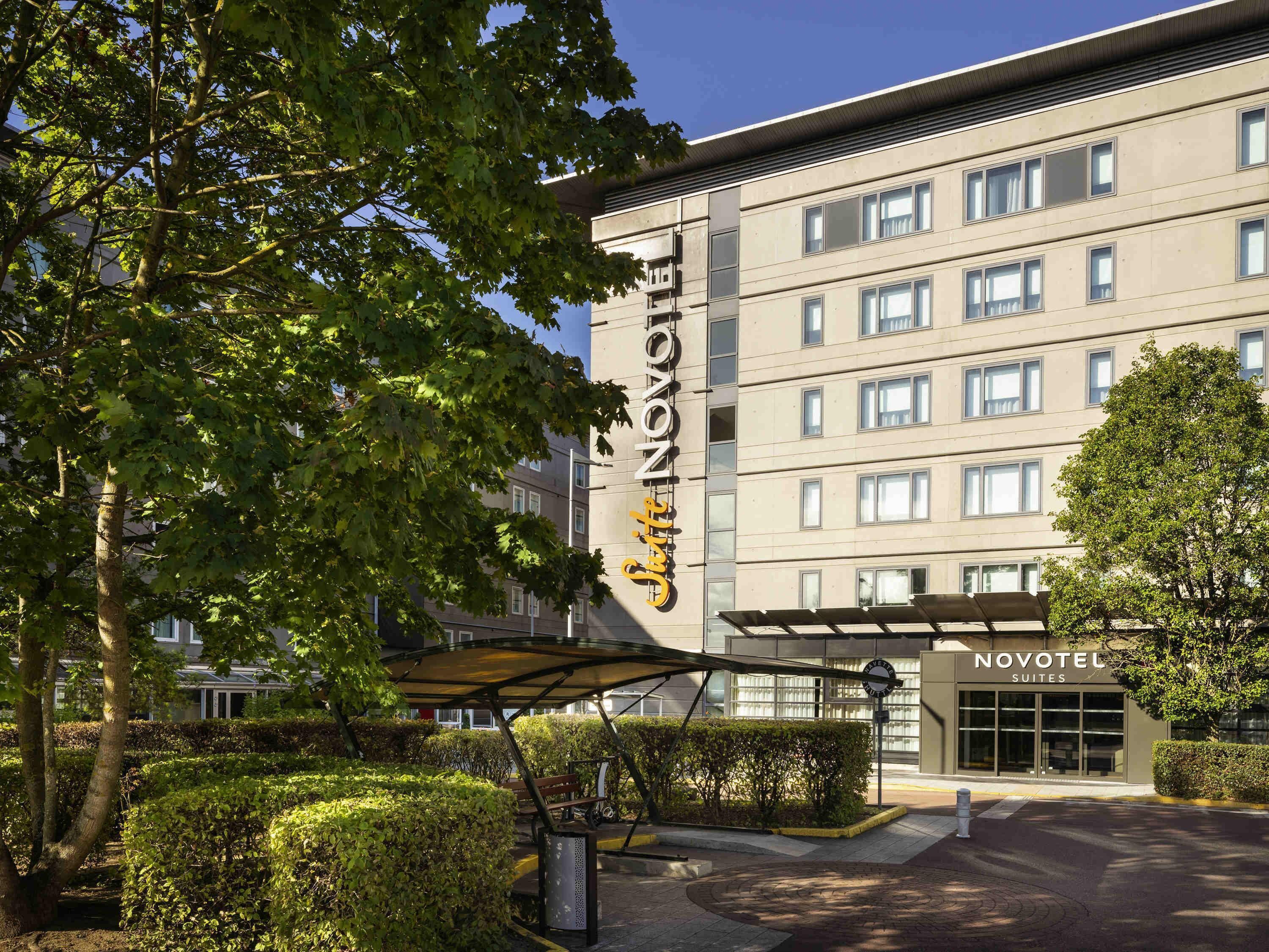 A modern hotel building with a prominent sign reading 'NOVOTEL SUITES.'