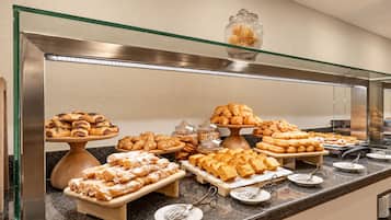 A buffet with various pastries and baked goods, including croissants and cookies, displayed on wooden stands and plates.