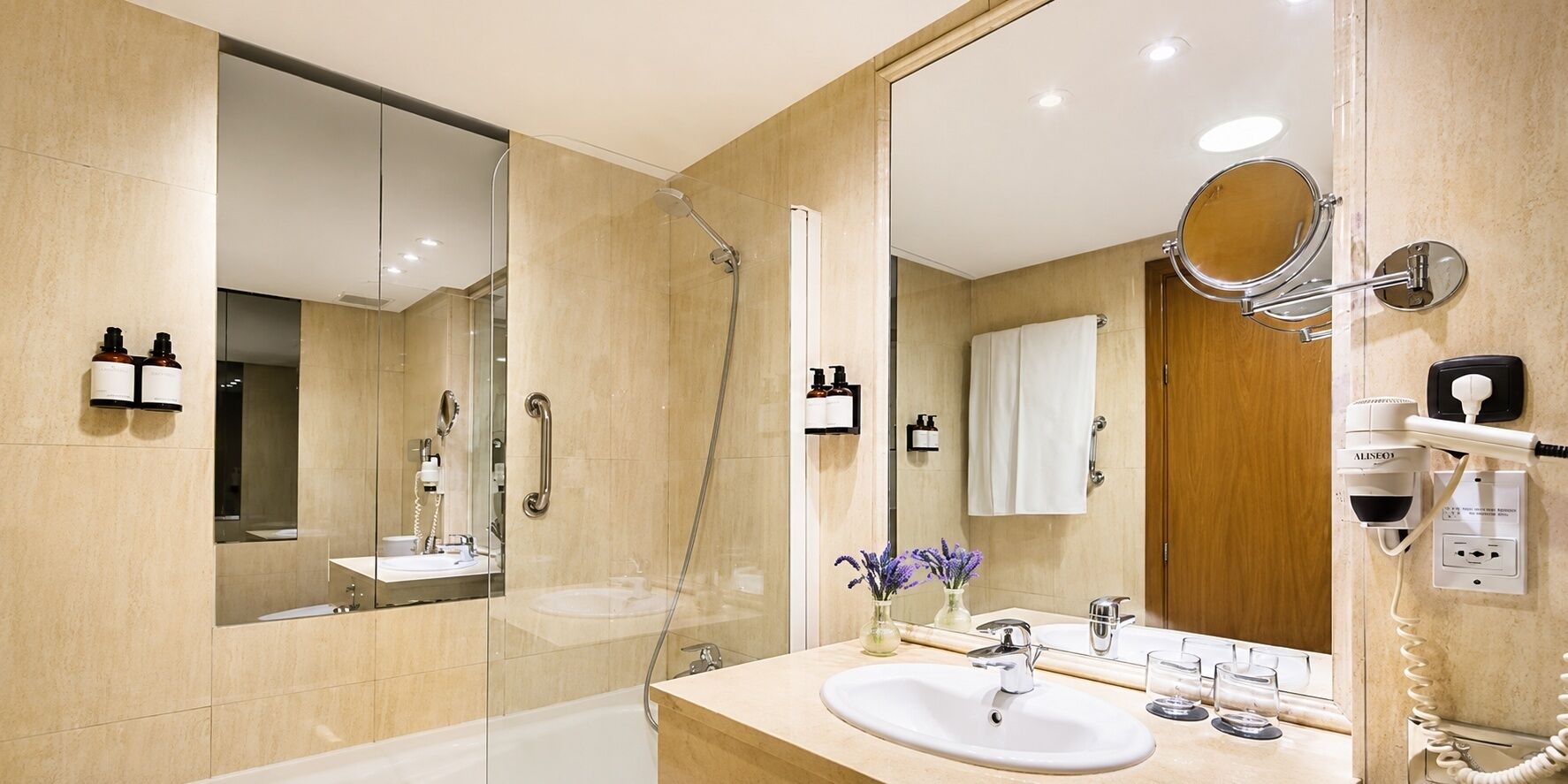 Un baño moderno con ducha envuelta en vidrio, un lavamanos con espejo y un perchero para toallas.