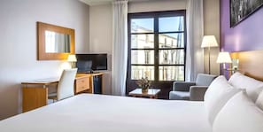 Una habitación de hotel con cama, escritorio, televisor y dos sillas.