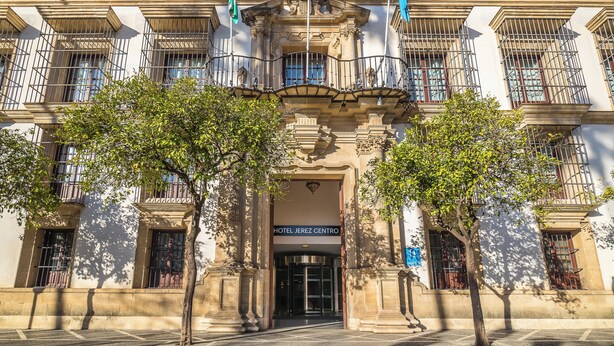 Un edificio histórico con fachada clásica, entrada central y varios balcones.