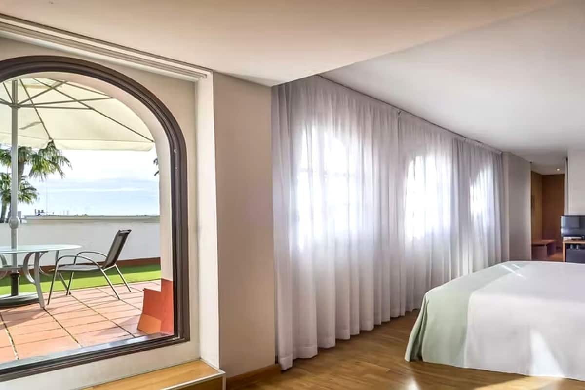 Une chambre d’hôtel équipée d’un lit, d’une télévision, d’un bureau et d’un balcon avec une table et des chaises.
