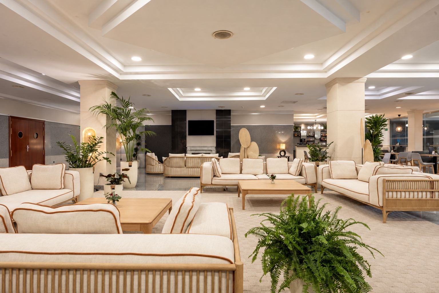 Een ruime lobby met een modern design, met banken, een bijzettafeltje en potplanten.
