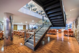 Un interior moderno con una escalera espiral central, suelo de madera y un entrepiso con asientos.