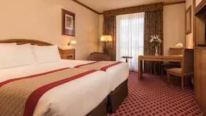 Een hotelkamer met een groot bed, een bureau, een stoel en een lamp.