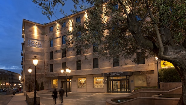 Een hotel met meerdere verdiepingen, een opvallende ingang en een binnentuin met een fontein.