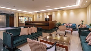 Een hotel lobby met een receptiebalie, banken en een bijzettafeltje.