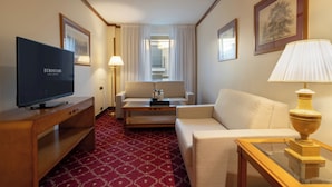 Een hotelkamer met een televisie, een bank, een bijzettafeltje en een lamp.