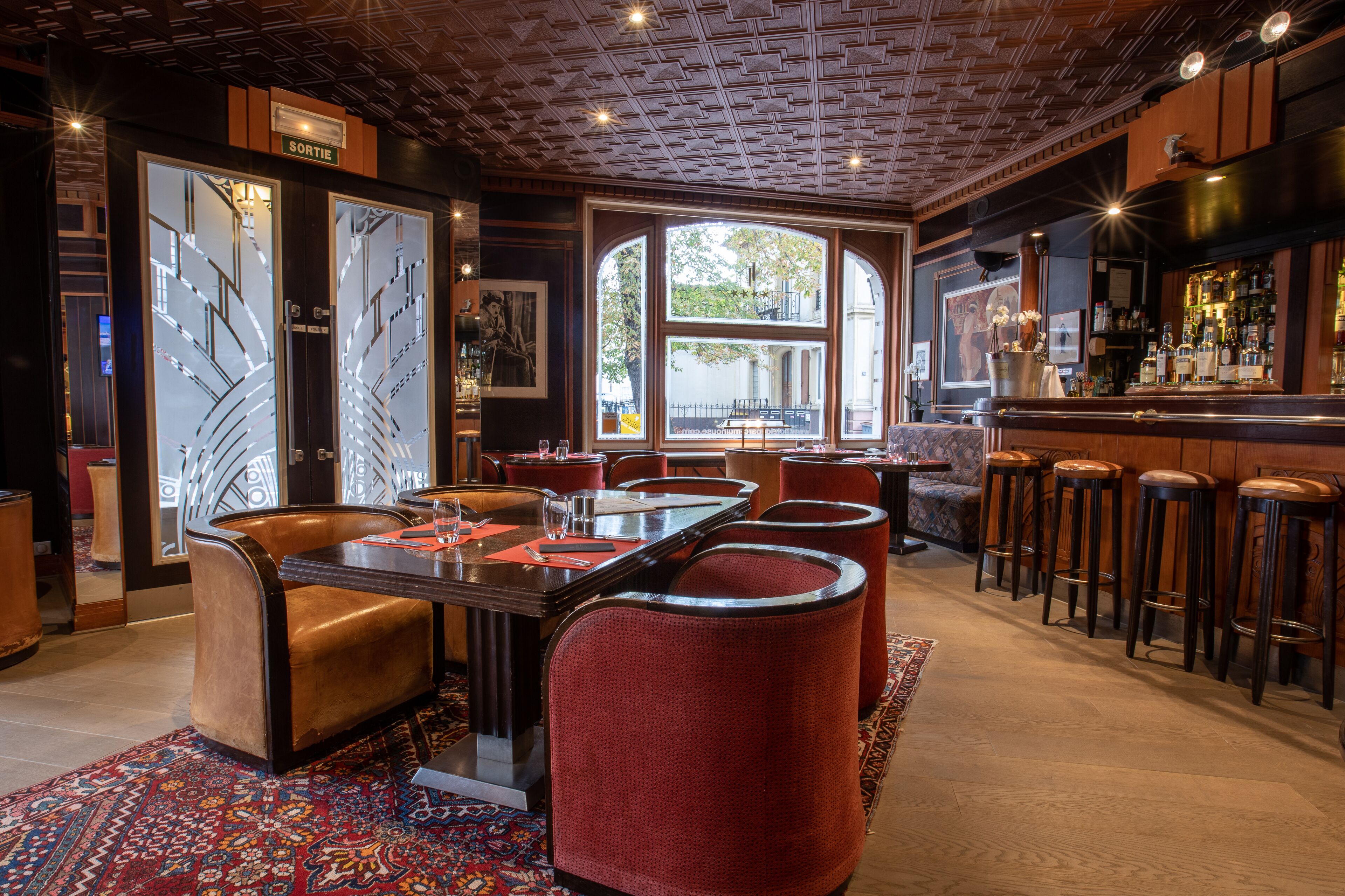 A restaurant with a bar area, a large window with a view, and a patterned carpet.