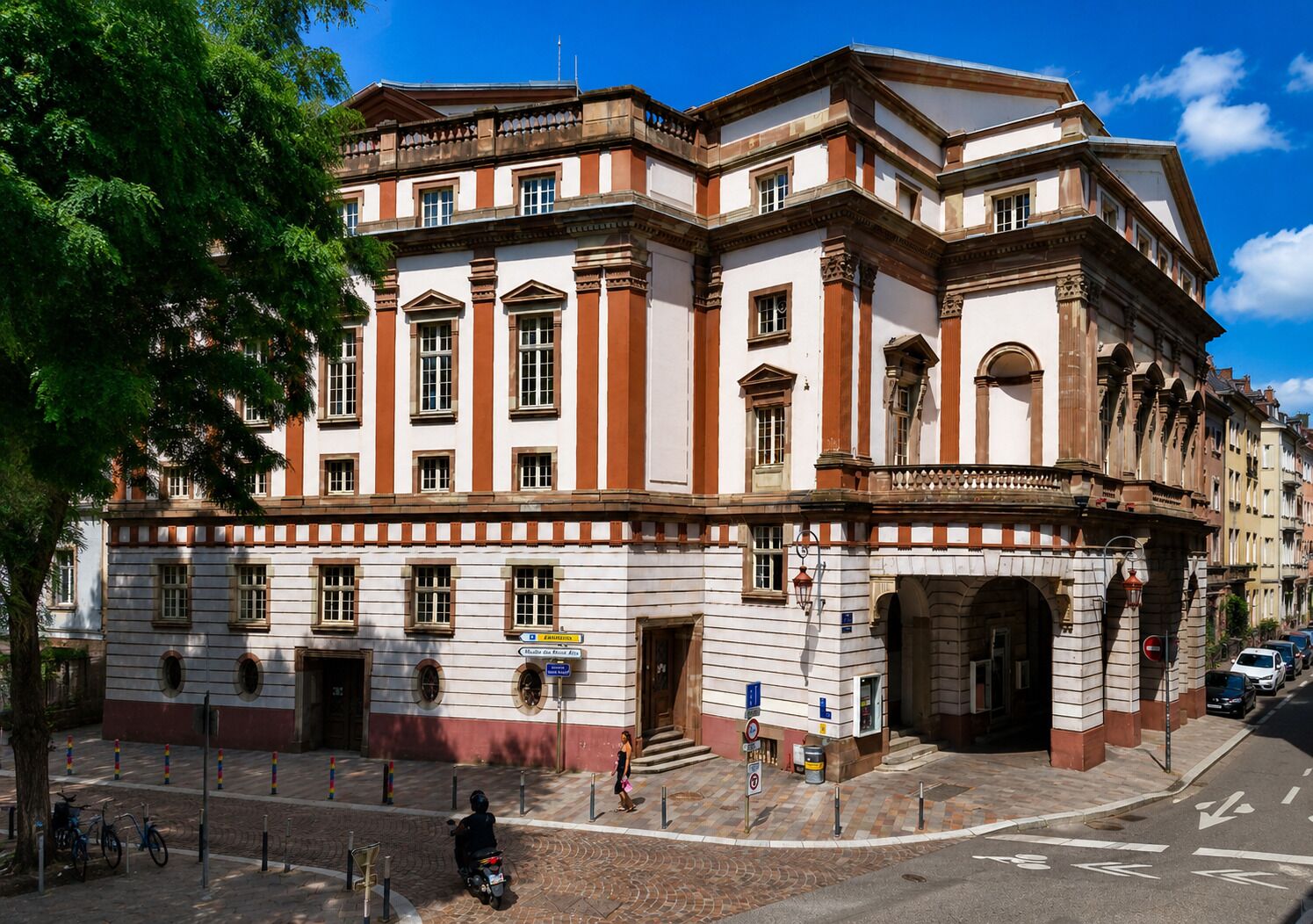 Een historisch gebouw met klassieke architectuur, met een opvallende ingang, meerdere ramen en een hoekligging.