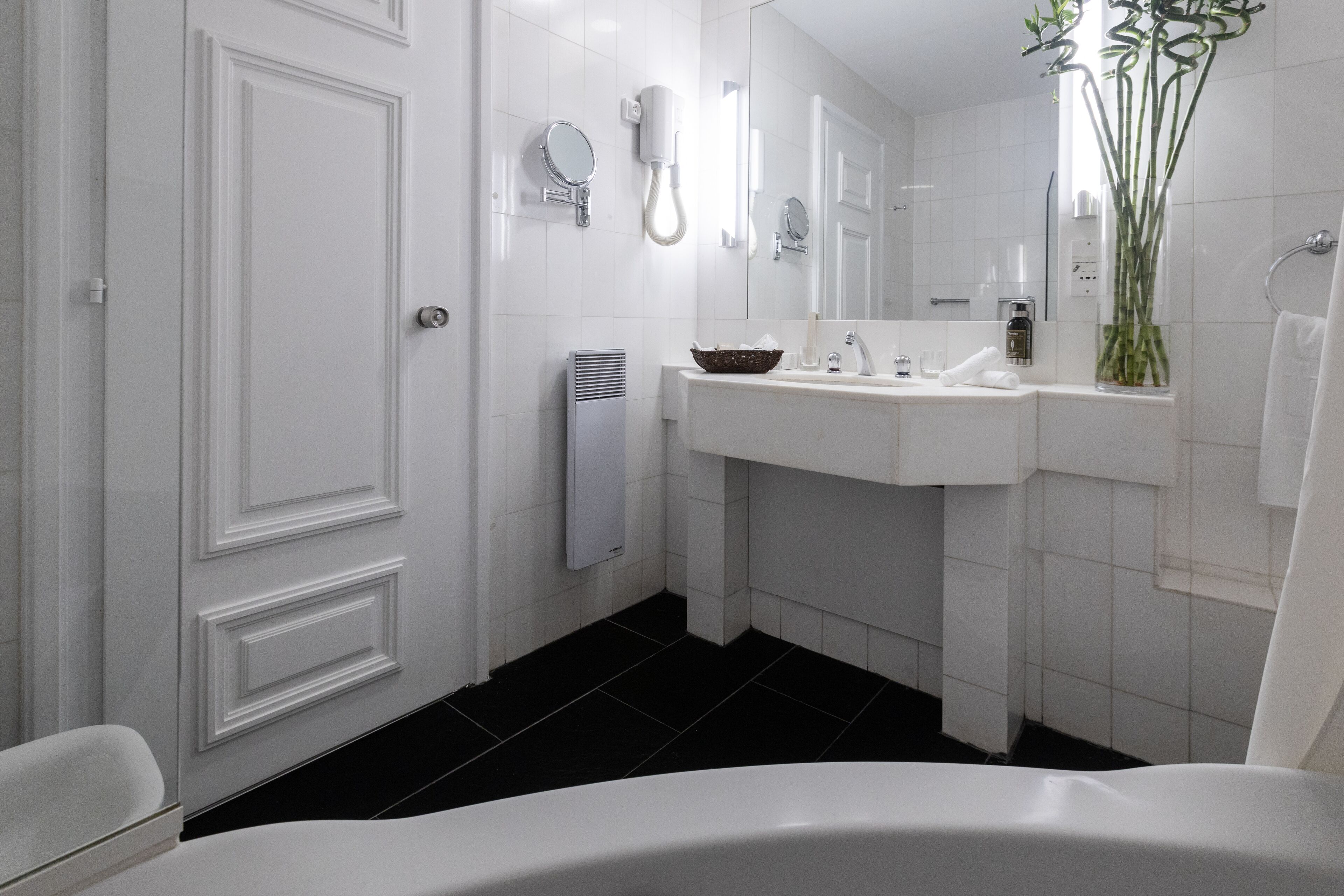 A modern bathroom with a white bathtub, a sink, and a mirror.