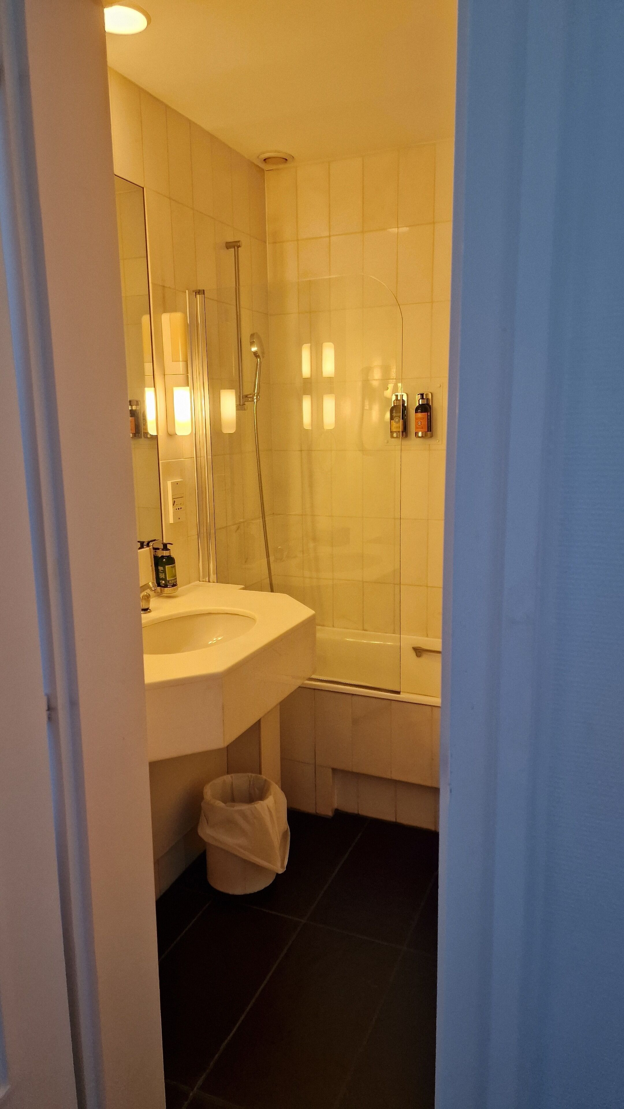 A bathroom with a sink, mirror, and shower.