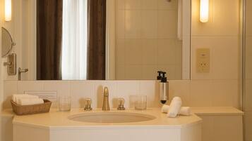A hotel bathroom with a large mirror, a sink with a faucet, a towel rack, and a glass of water on the counter.